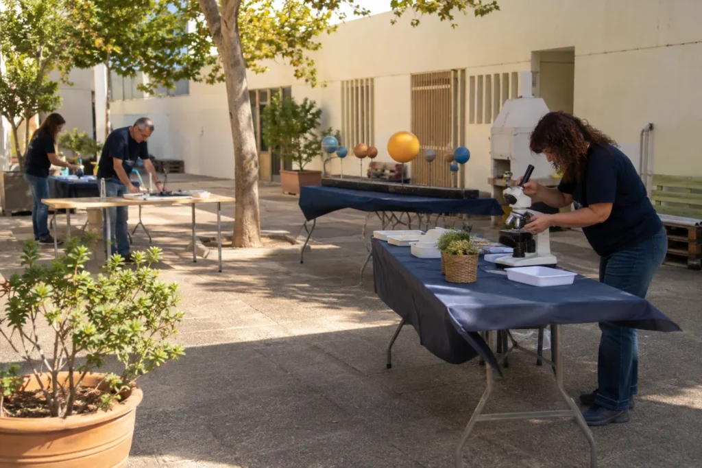 מתנדבים מכינים ציוד ועמדות ליום מדע בחצר קהילתית